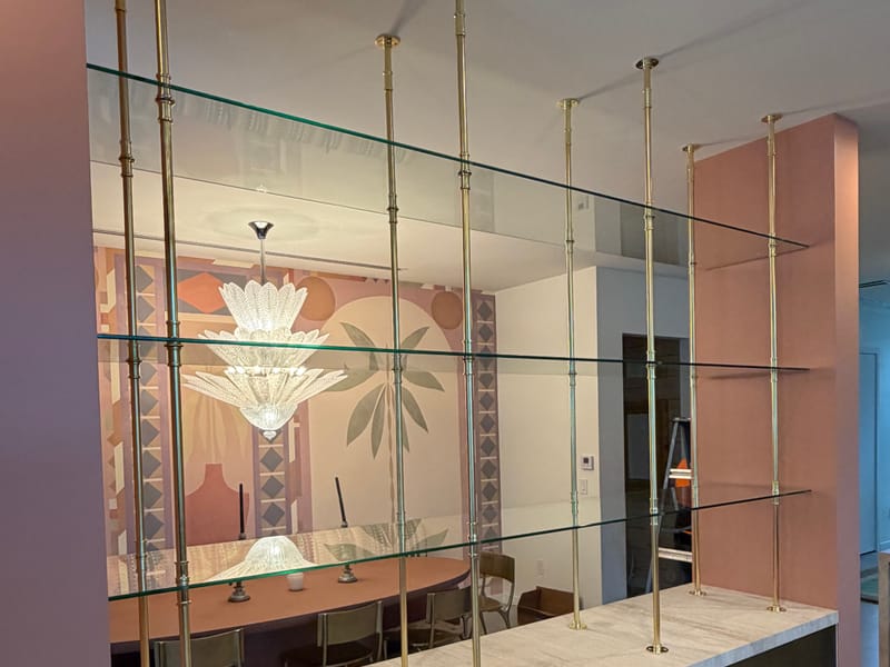 Floating glass shelves on brass rods with a mirrored back in a home bar