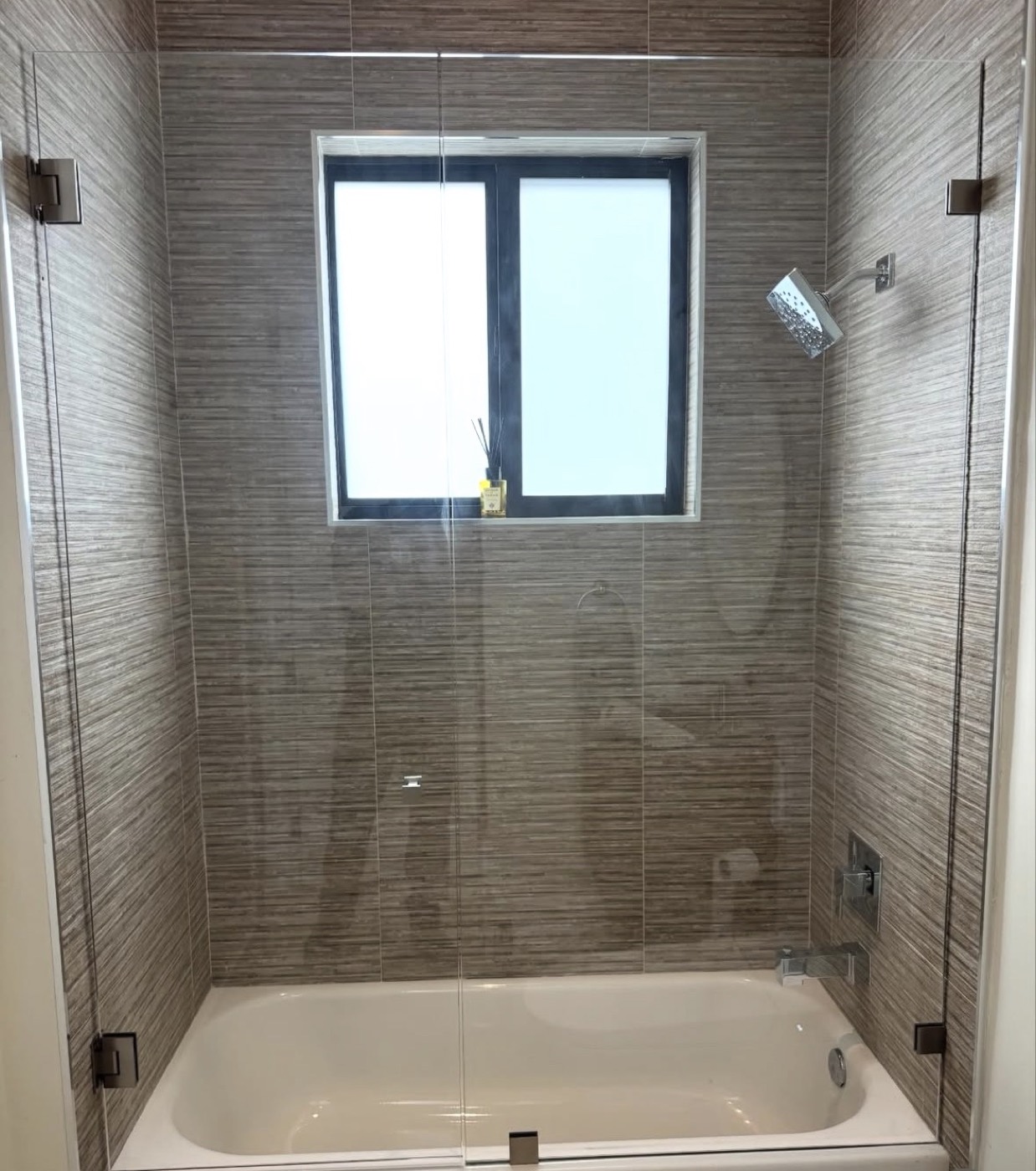 Fixed glass panels over a bathtub in a tan tiled bathroom